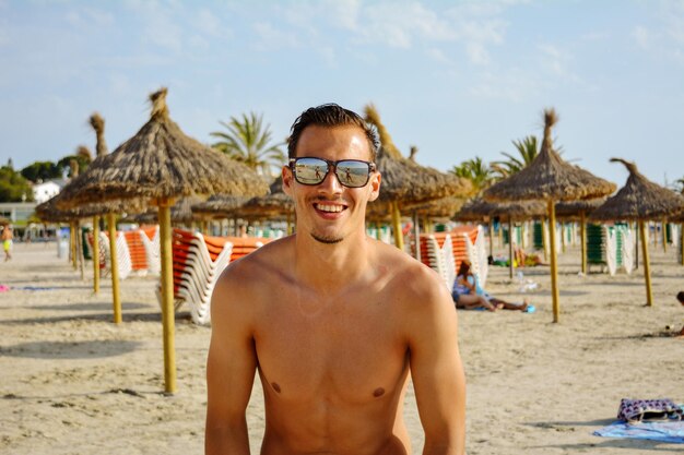 Foto retrato de un joven sin camisa en la playa contra el cielo