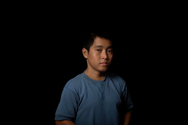 Retrato de un joven con camiseta azul mirando a la cámara en el espacio de copia de fondo negro