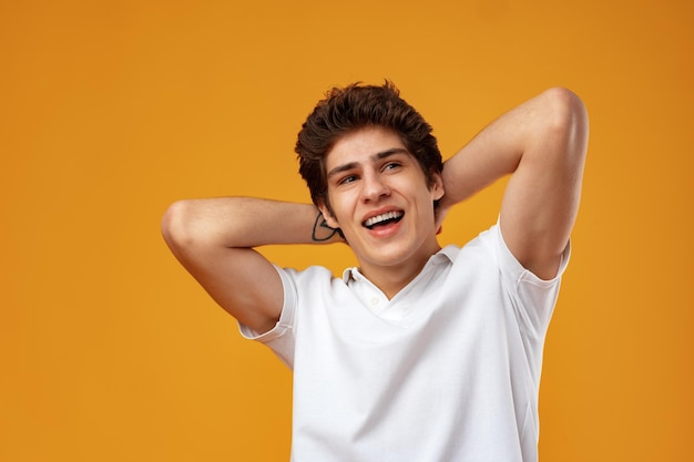 Retrato de un joven casual feliz de pie sobre fondo amarillo