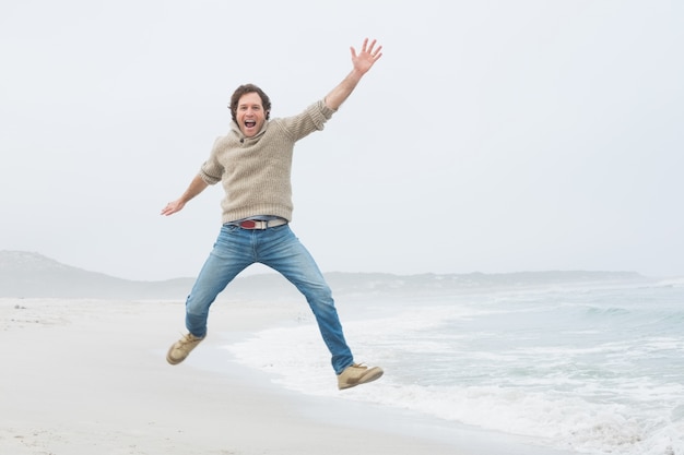 Retrato de un joven casual saltando en la playa