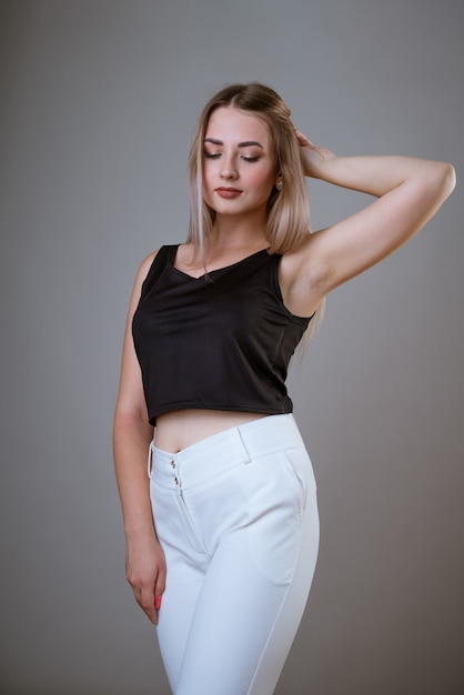 Retrato de una joven caucásica feliz en una camiseta negra posando sobre una pared de luz