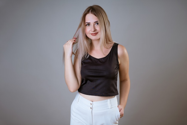 Retrato de una joven caucásica feliz en una camiseta negra posando sobre una pared de luz