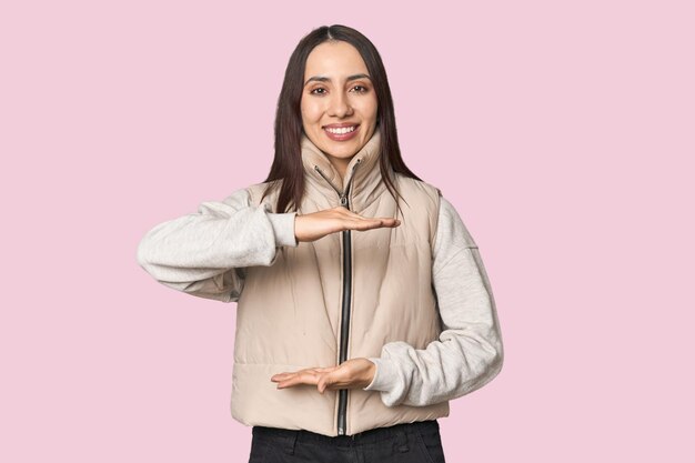 Retrato de una joven caucásica moderna en el fondo del estudio sosteniendo algo con ambas manos