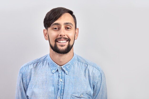 Foto retrato de joven caucásica morena barbuda hombre positivo sonriendo aislado sobre fondo blanco de estudio