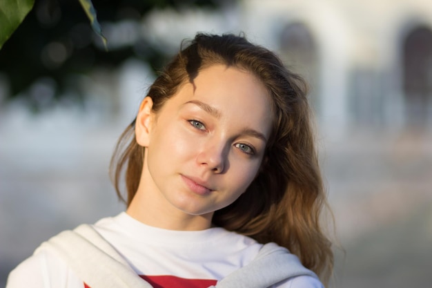 Retrato de una joven caucásica en el parque de verano mirando a la cámara