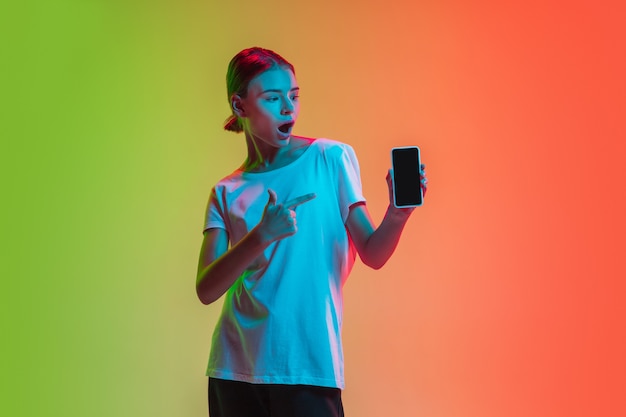 Retrato de joven caucásica sobre fondo degradado de estudio verde-naranja en luz de neón