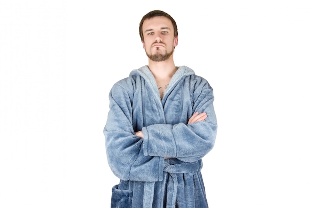 Foto retrato de joven caucásico barbudo orgulloso hombre en bata de baño azul con las manos cruzadas aislado sobre fondo blanco.