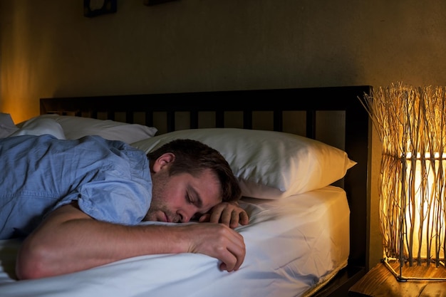 Retrato de un joven caucásico cansado acostado en la cama usando una laptop durante mucho tiempo