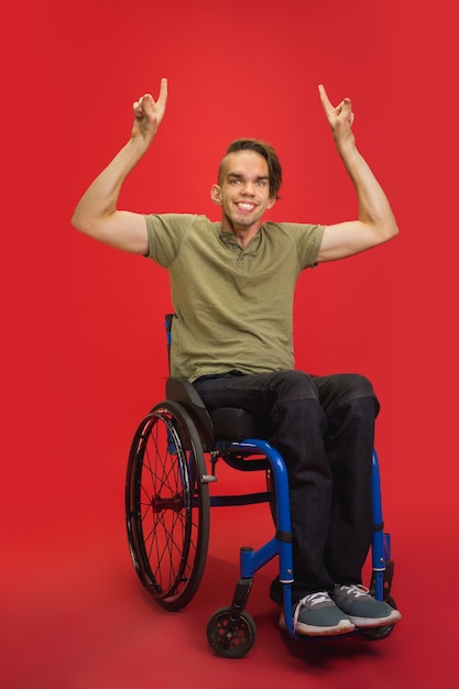 Retrato de joven caucásico discapacitado aislado sobre fondo rojo de estudio.