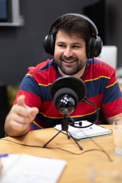 Retrato de un joven caucásico sonriente con auriculares trabajando en una estación de radio