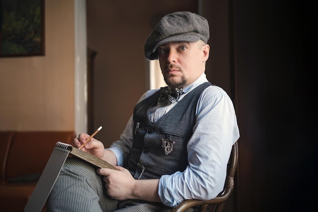 Retrato de un joven con chaleco de tweed y gorra sentado con un bloc de notas en el interior