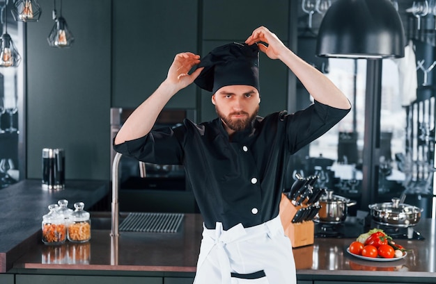 Foto retrato de un joven chef profesional uniformado que posa para la cámara en la cocina