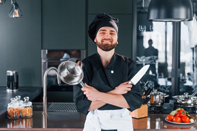 Retrato de un joven chef profesional uniformado que posa para la cámara en la cocina