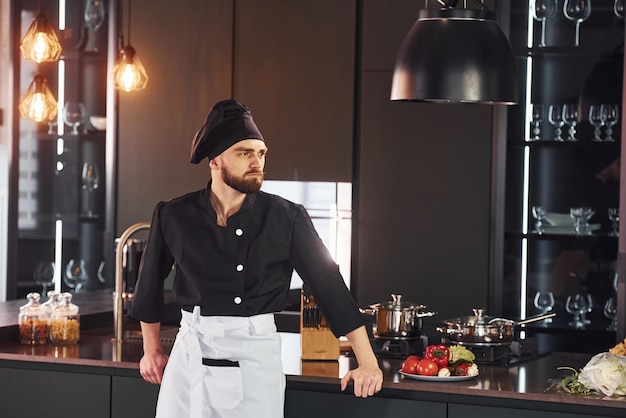 Retrato de un joven chef profesional uniformado que posa para la cámara en la cocina