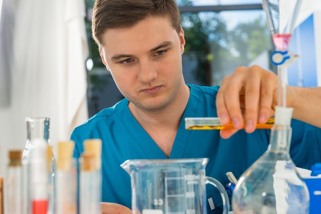 Retrato de joven científico concentrado en uniforme trabajando en algunas investigaciones en un laboratorio. Concepto de salud y biotecnología