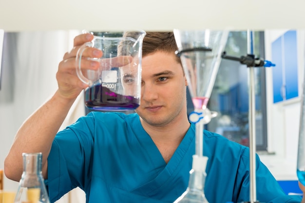 Retrato de joven científico en uniforme trabajando en una investigación en un laboratorio. Concepto de salud y biotecnología