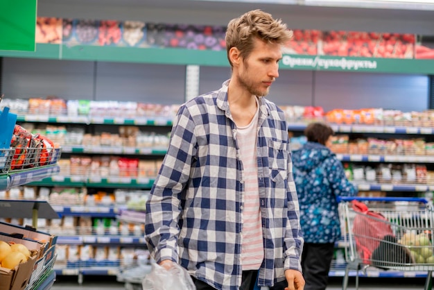 Retrato de joven cliente caminar en supermercado b