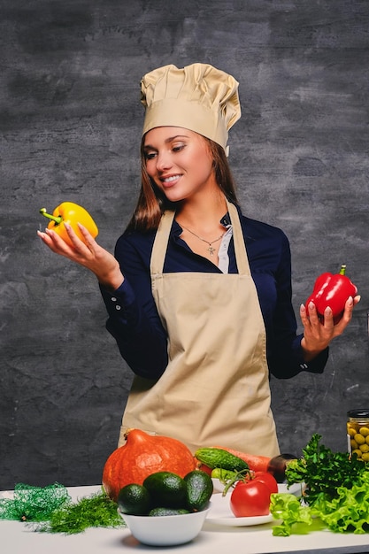 Retrato de una joven cocinera tiene verduras.