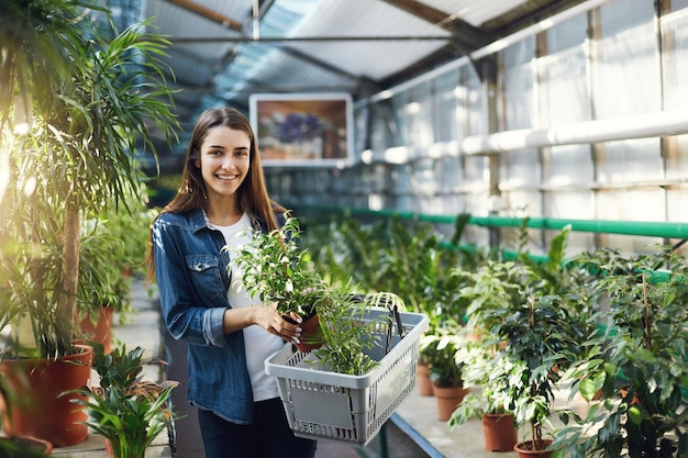 Retrato de una joven compradora caminando por una tienda de jardín interior mirando a la cámara sonriendo