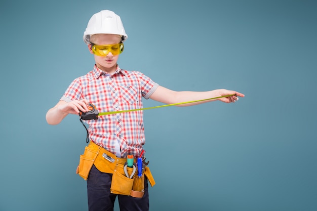 Retrato de un joven constructor en un casco y una cinta métrica en la mano