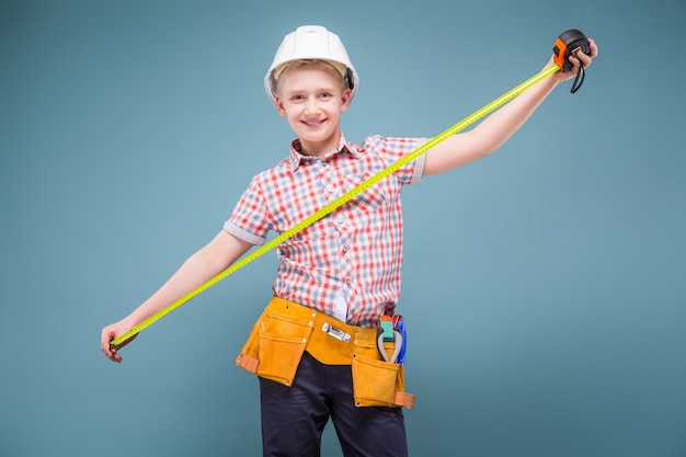 Retrato de un joven constructor en un casco y una cinta métrica en la mano