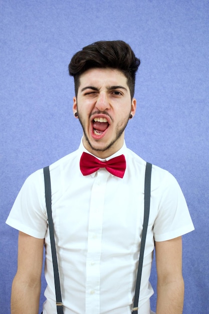 Foto retrato de un joven con corbata de pajarita contra un fondo azul