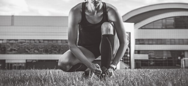 Retrato de una joven corredora que ata sus botas en un estadio de fútbol. Concepto deportivo.