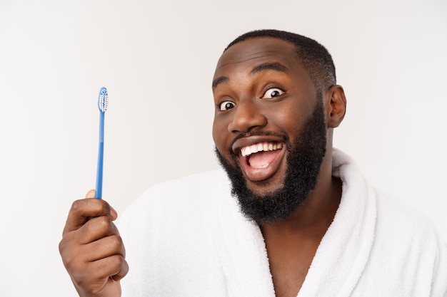 Retrato de un joven darkanm feliz cepillándose los dientes con pasta de dientes negra sobre un fondo blanco