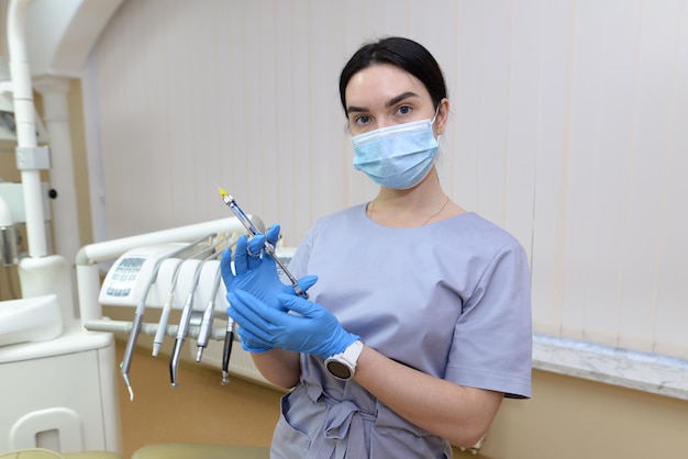 Retrato de una joven dentista con una máscara médica con una jeringa en la mano. El concepto de medicina, odontología y atención médica.