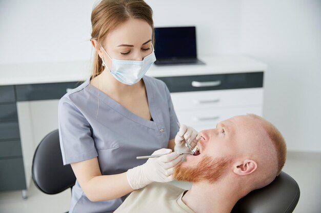 Retrato de una joven dentista parada junto a un hombre adulto medio en la clínica