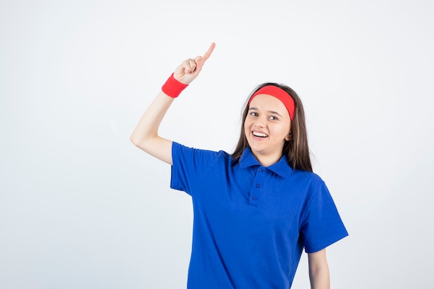 Foto retrato de una joven deportista de pie y apuntando hacia arriba