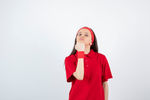 Retrato de una joven deportista de pie y posando sobre una pared blanca