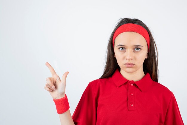 Retrato de una joven deportista de pie y posando sobre una pared blanca