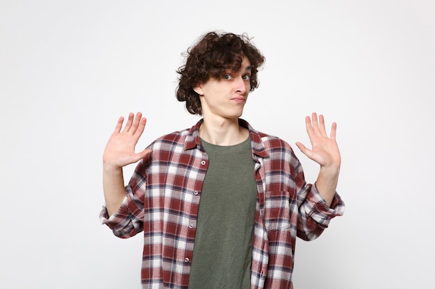 Retrato de joven desconcertado en ropa casual mirando a cámara, extendiendo las manos, mostrando palmas aisladas sobre fondo blanco en estudio. Personas sinceras emociones, concepto de estilo de vida. Simulacros de espacio de copia.