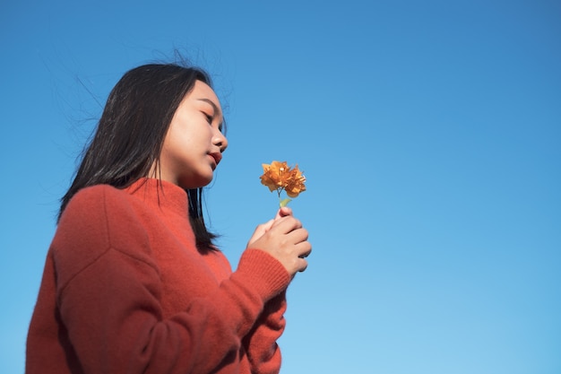 Retrato joven desgaste orang swater con flor orang con fondo de cielo azul.