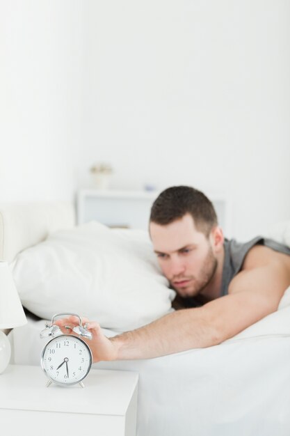 Foto retrato de un joven despierto por un despertador