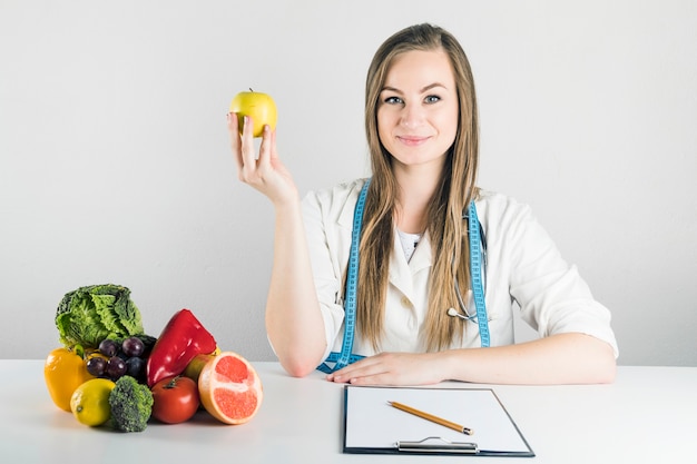 Foto retrato de una joven dietista femenina con manzana