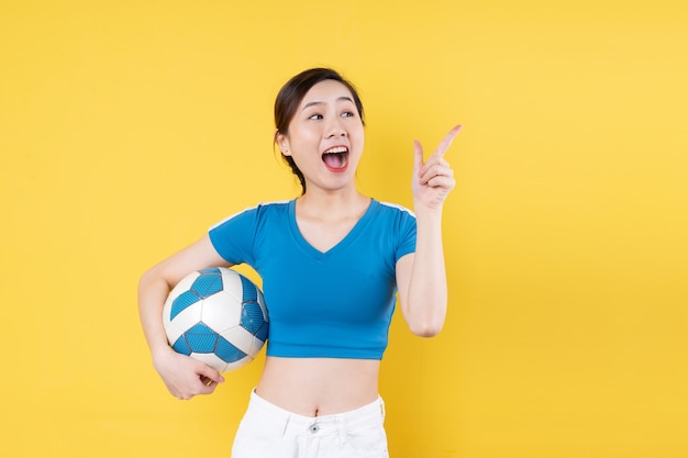 Retrato de joven dinámica sosteniendo la bola en la mano aislado sobre fondo amarillo