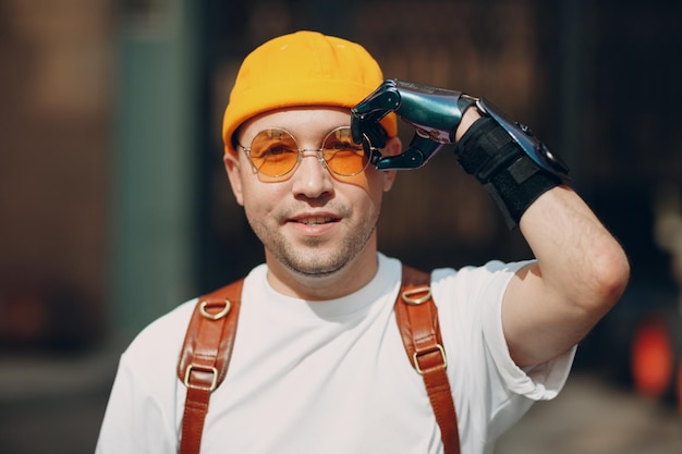 Retrato de joven discapacitado ponerse gafas amarillas con prótesis de mano artificial