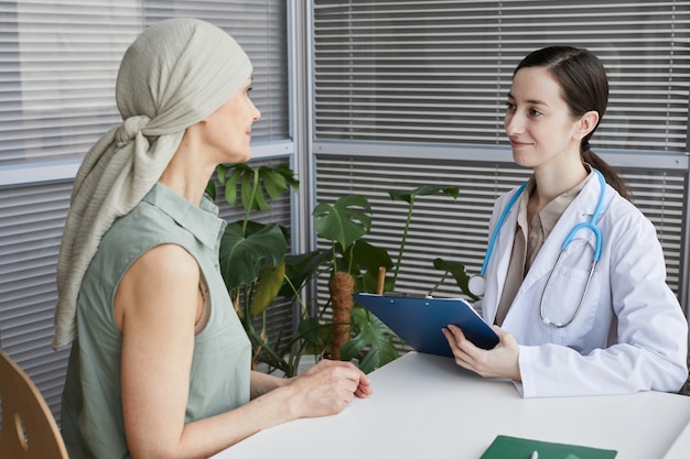 Retrato de joven doctora hablando con el paciente durante la consulta en la clínica médica, espacio de copia