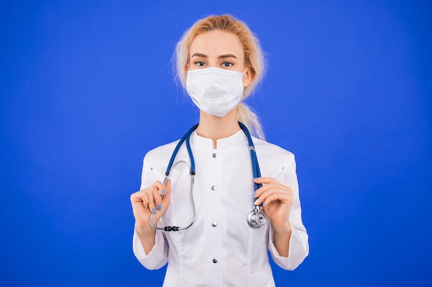 Retrato de una joven doctora con una máscara protectora sobre un fondo azul.