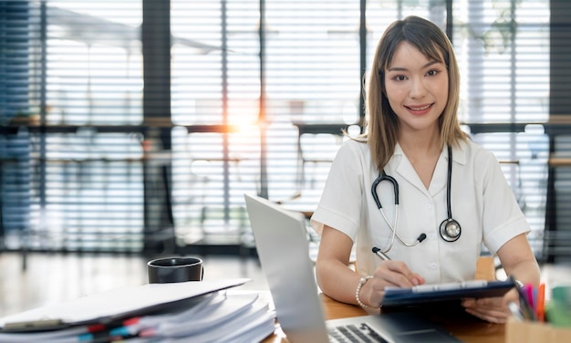 Retrato de una joven doctora o enfermera caucásica sonriente con uniforme médico blanco en la clínica