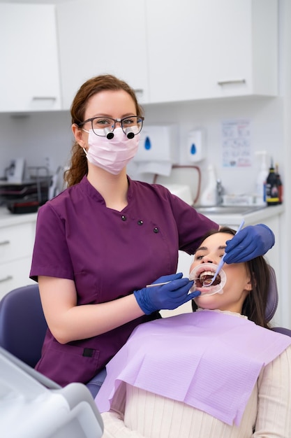 Retrato de una joven doctora que realiza un tratamiento dental a un paciente