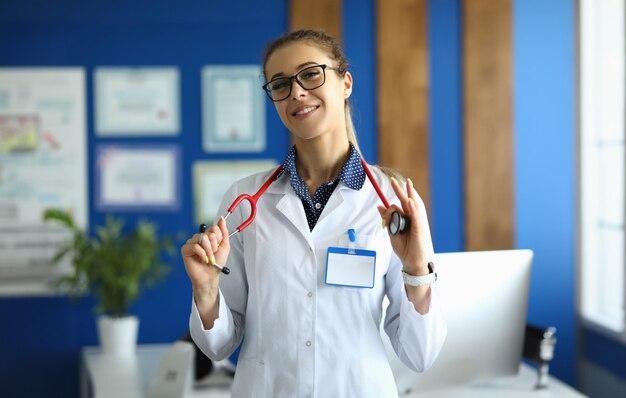 Foto retrato de una joven doctora sonriente con gafas doctor cardiólogo terapeuta en clínica y seguros y servicios de salud