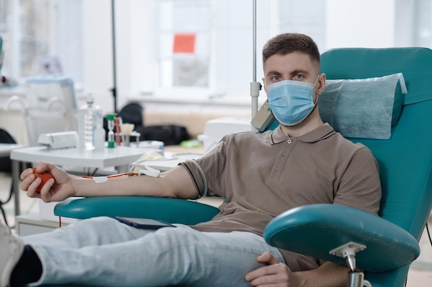 Retrato de un joven donante de sangre con máscara médica