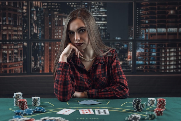 Retrato de una joven elegante y elegante con cartas y fichas de casino jugando al póquer