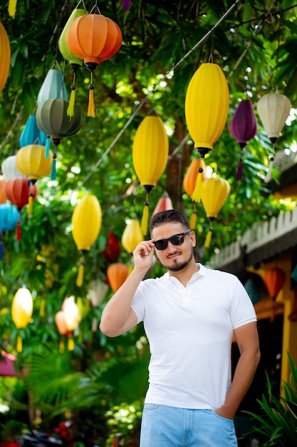 Retrato de un joven elegante con gafas de sol en la calle, estilo de vida. Estilo urbano. El hombre de gafas sonríe alegremente