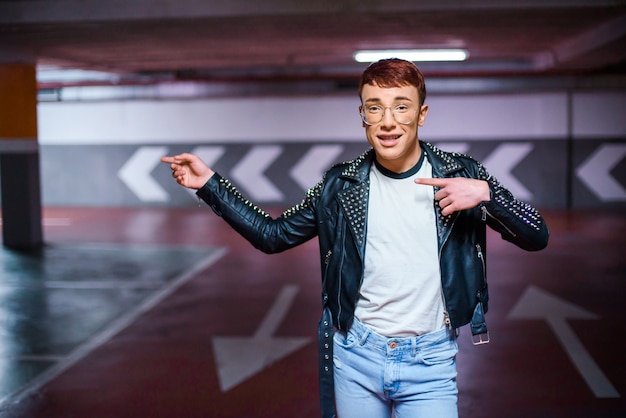 Retrato de un joven y elegante hombre weared señalando algo en un estacionamiento subterráneo