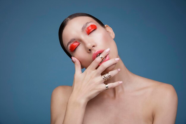 Retrato de una joven elegante con maquillaje rojo brillante sobre un fondo azul. Moda de belleza