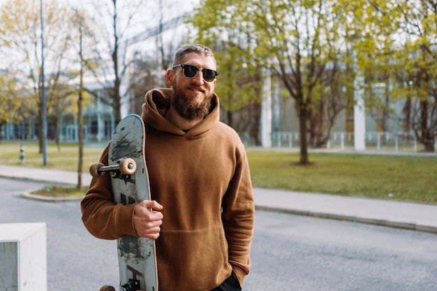 Retrato de un joven elegante sostiene una patineta en la mano Espacio de copia Foto de la mejor calidad